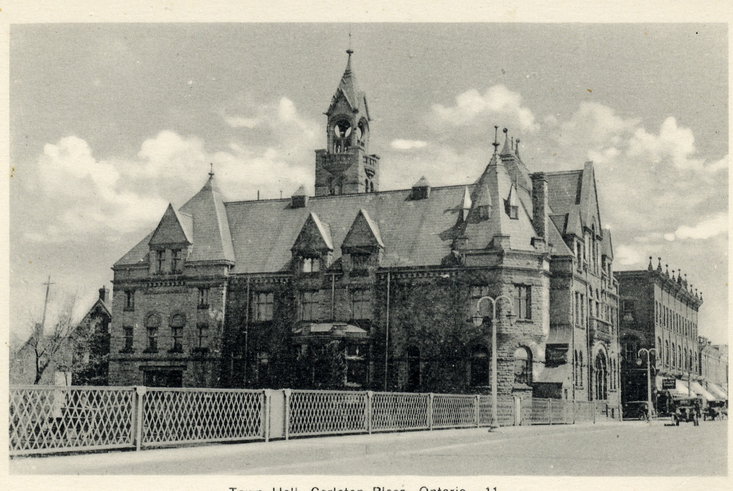 Black and white photograph of "Town Hall, Carleton Place, Ontario. - 11." Showing bridge, town hall and portions of Bridge Street. Car on street, street lamps, houses on Mill Street. Unused. Search term: Main Street